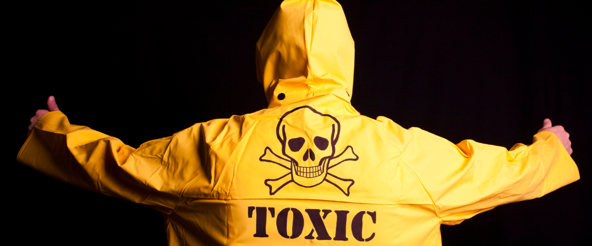 Human with a yellow jacket on and word toxic with the skull and cross bones symbol emblazoned on the back